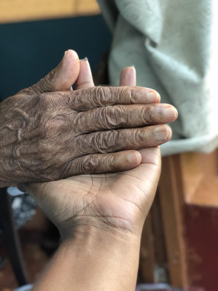 Black and white photo of CEO Nikki with her hands grasping her grandma’s hands. Image is only of their hands.