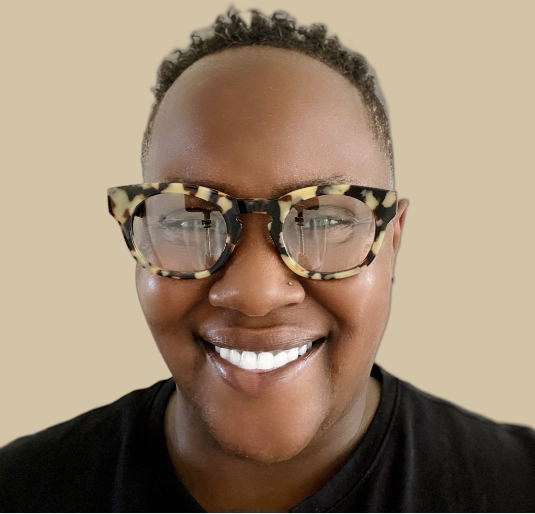 Headshot of Tonj’a. She has a huge smile, wearing glasses, and a black shirt.